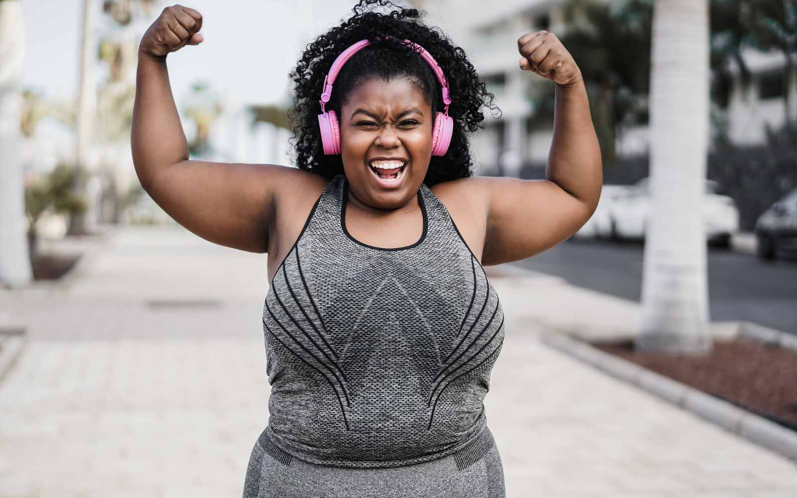 Happy curvy african woman doing workout routine outdoor at city park