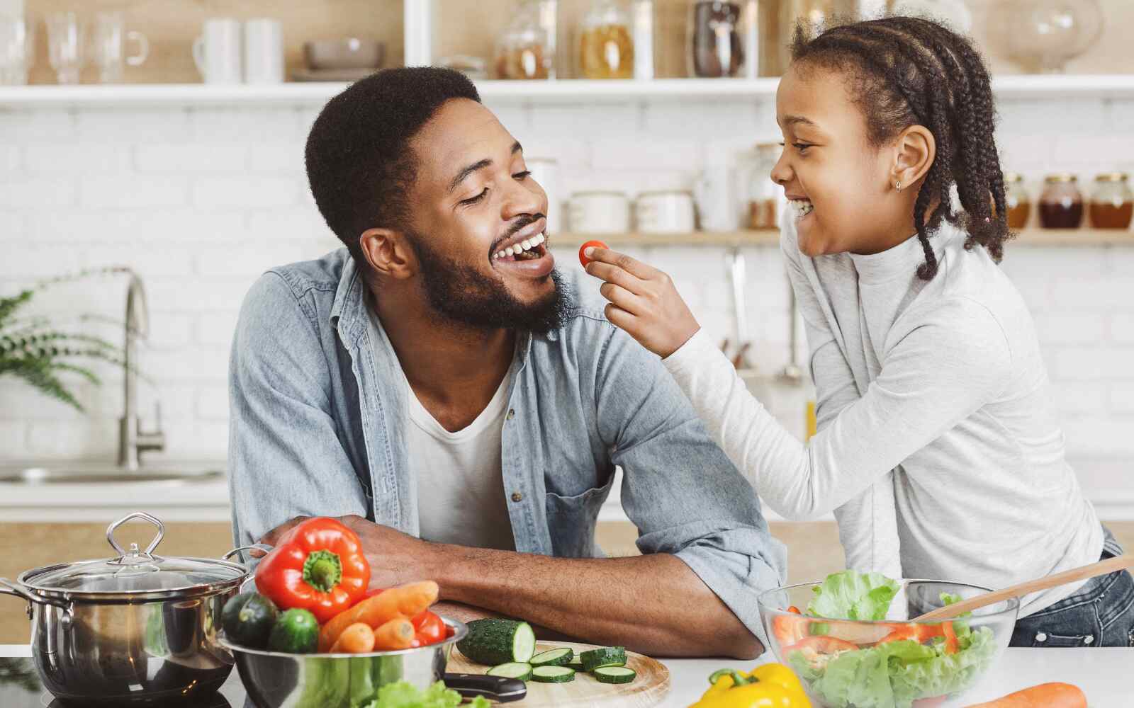 A dad and daughter are in their kitchen, sharing healthy foods together