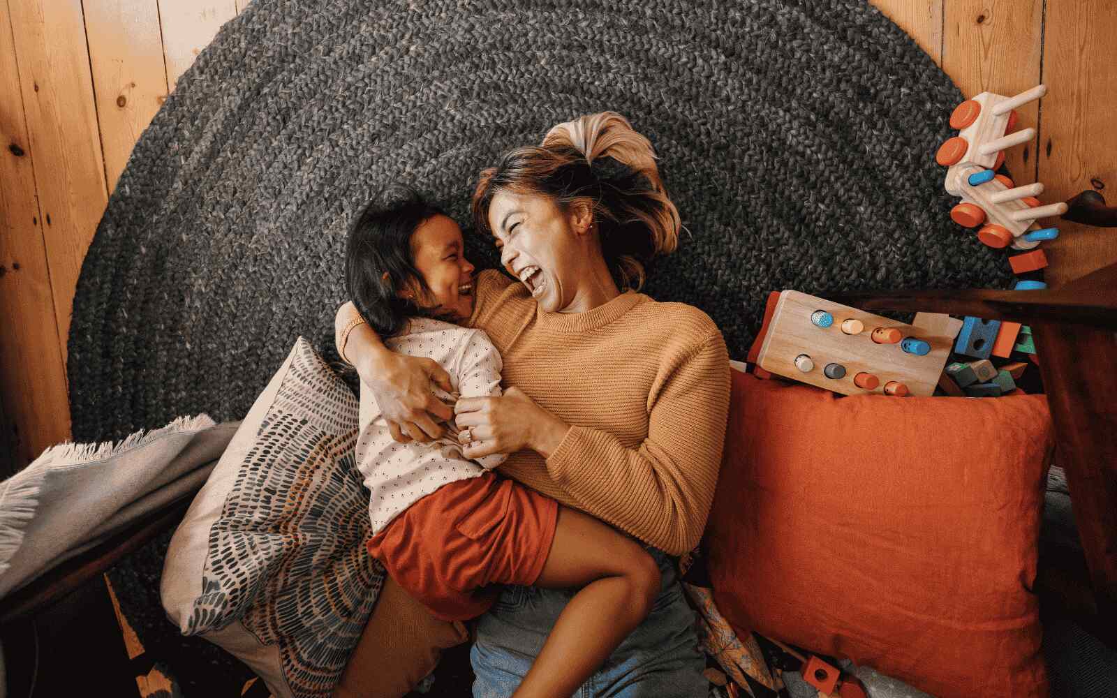 a mom and her child are laughing together while laying on the floor