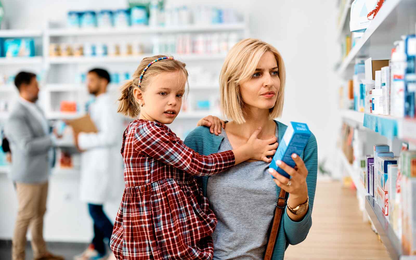 a mom and daughter shopping in a pharmacy, looking at supplements and reading labels